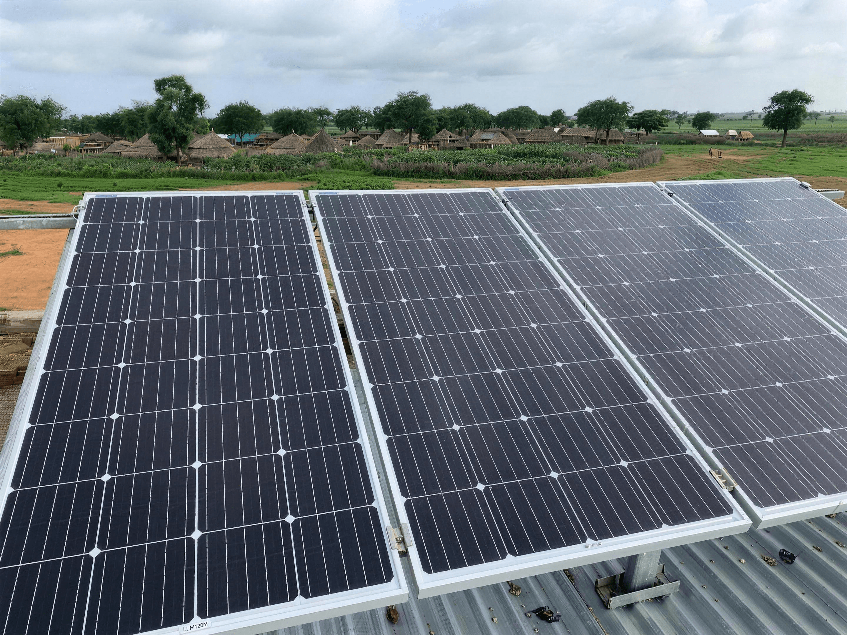 Solar panels on a village rooftop in Sudan, homes and trees behind
